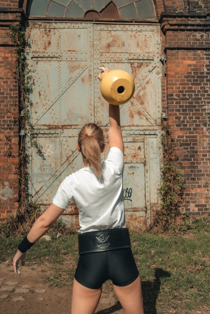 Athlete pressing an Incore Sports competition kettlebell overhead