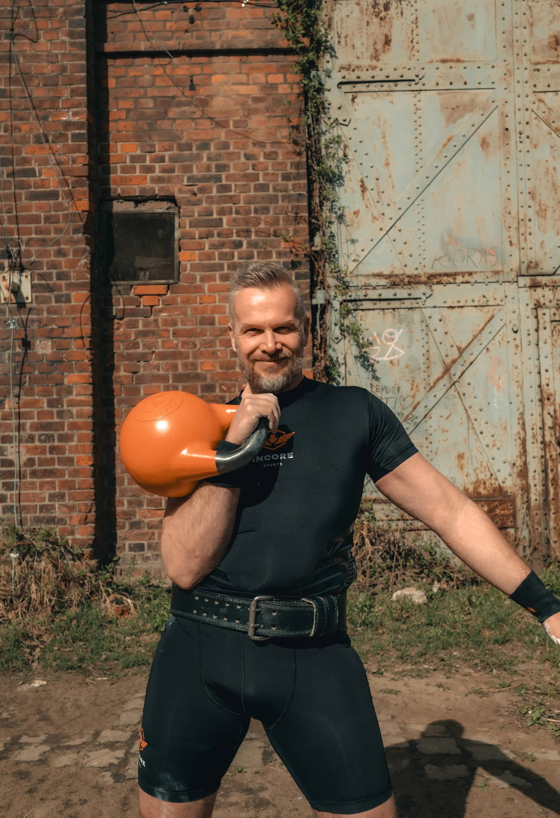 Athlete holding an orange Incore Sports competition kettlebell in the rack position