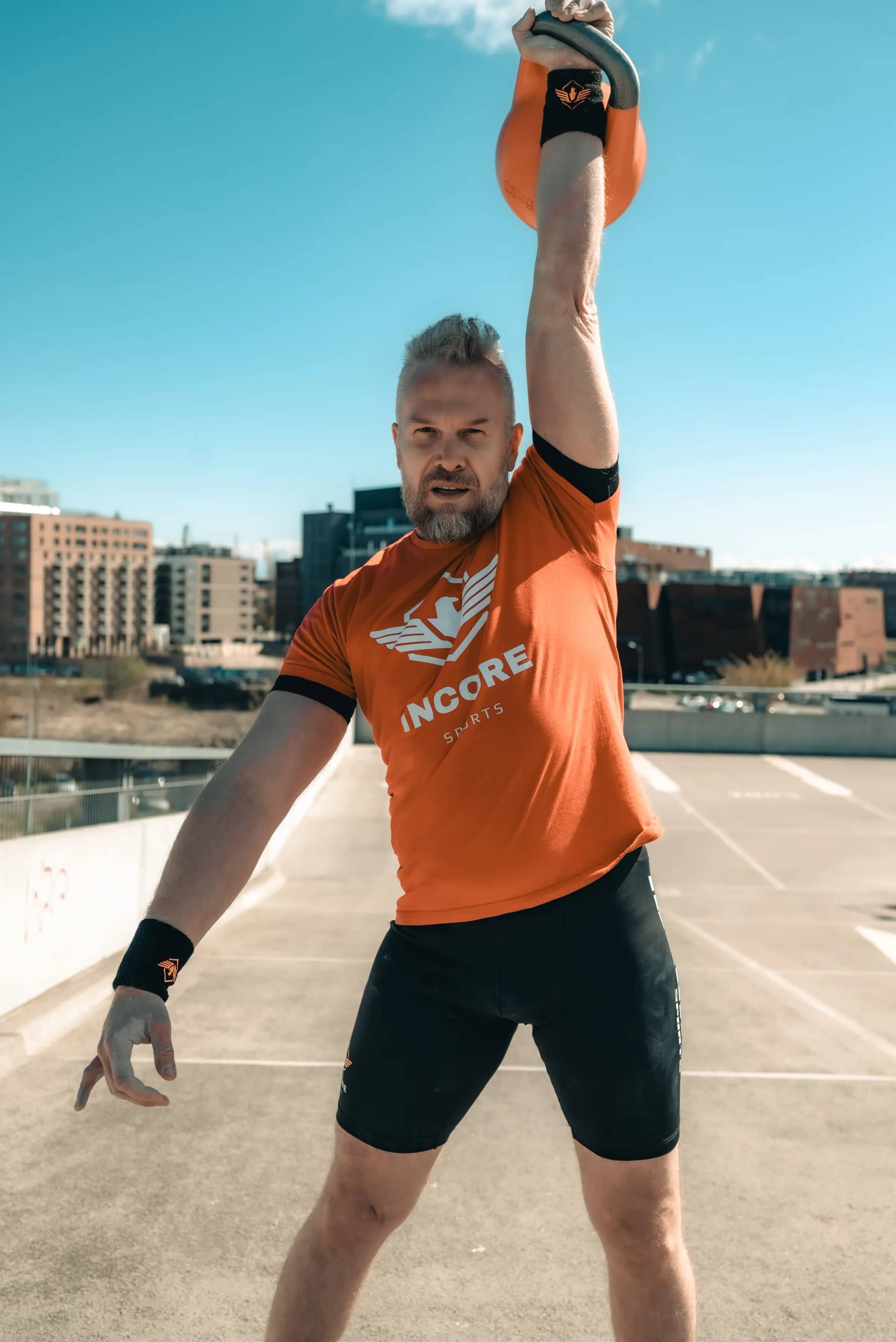 Zawodnik wykonujący wycisk kettlebell w odzieży Incore Sports